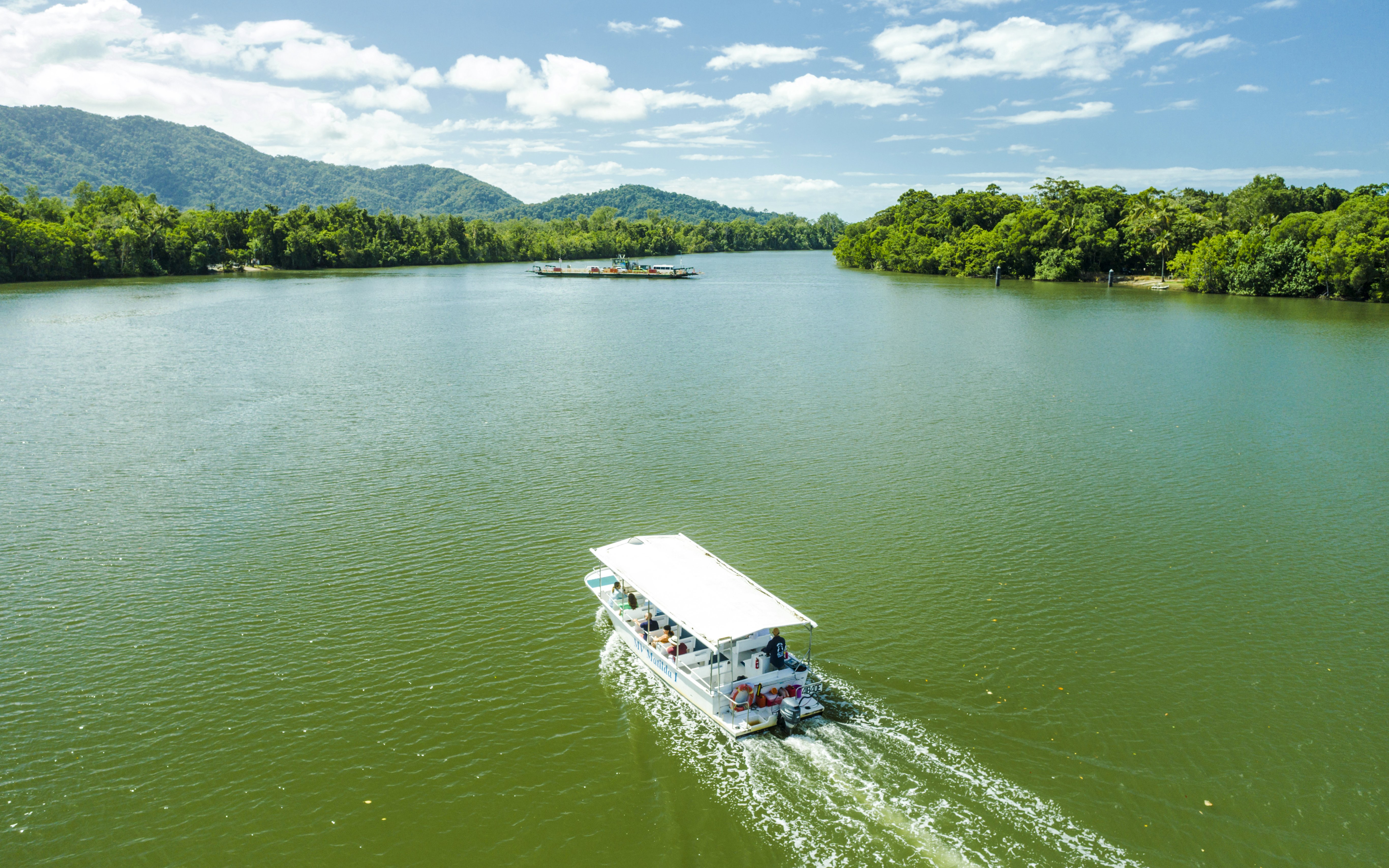 Boat cruising on a river surrounded by lush greenery in Daintree, part of Billy Tea Safaris tour.