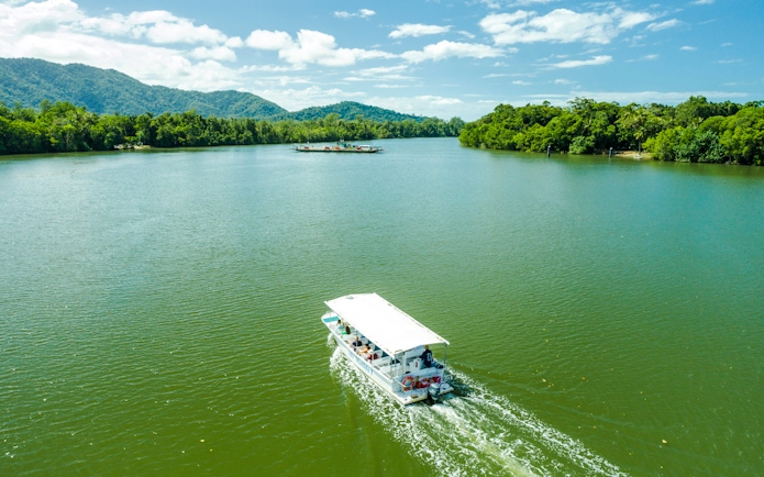 Boat cruising on a river surrounded by lush greenery in Daintree, part of Billy Tea Safaris tour.