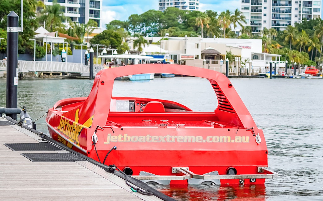 Red jet boat docked at marina, ready for Ultimate Jet Boat Ride and Surf Lesson.