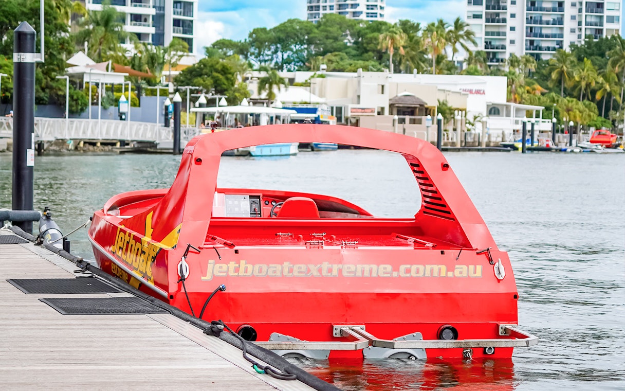 Red jet boat docked at marina, ready for Ultimate Jet Boat Ride and Surf Lesson.