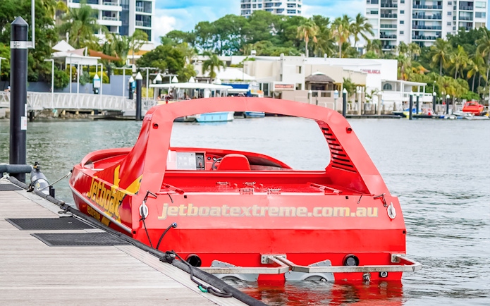 Red jet boat docked at marina, ready for Ultimate Jet Boat Ride and Surf Lesson.