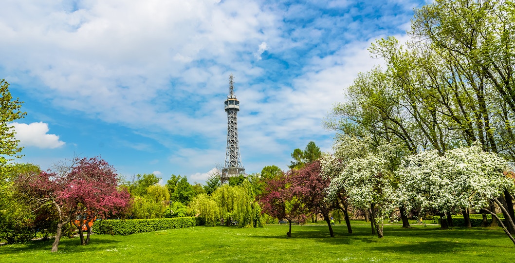 Petrin Tower surrounded by lush gardens and blooming trees in Prague.