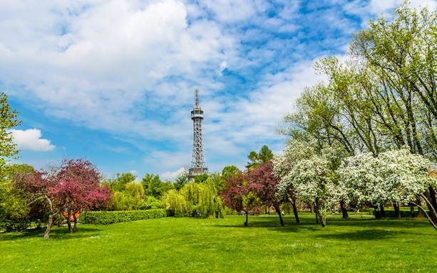 Petrin Tower surrounded by lush gardens and blooming trees in Prague.