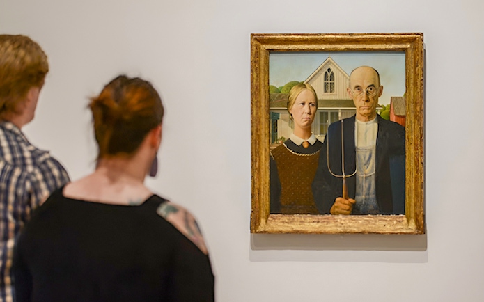 Visitors viewing "American Gothic" painting at Whitney Museum exhibit.