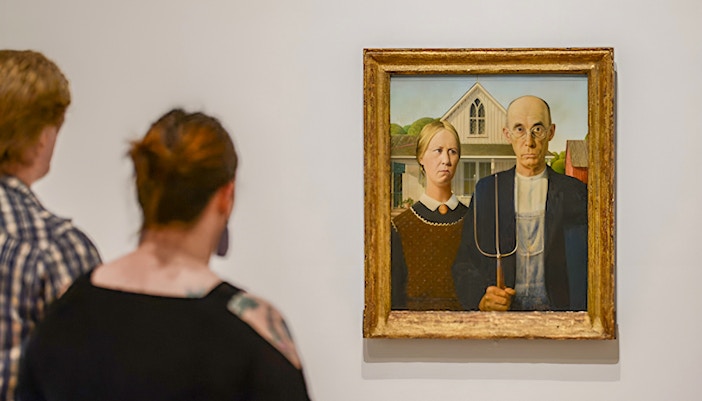 Visitors viewing "American Gothic" painting at Whitney Museum exhibit.