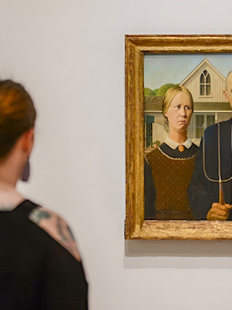 Visitors viewing "American Gothic" painting at Whitney Museum exhibit.