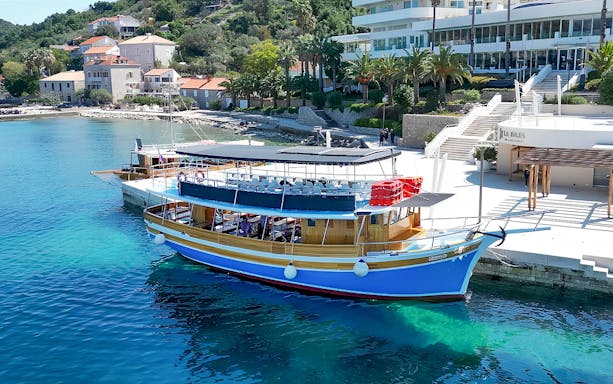 Boat docked along the shores of Elaphiti Islands with coastal buildings in the background.