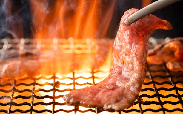 Grilling Yakiniku meat over open flame on a barbecue grill.