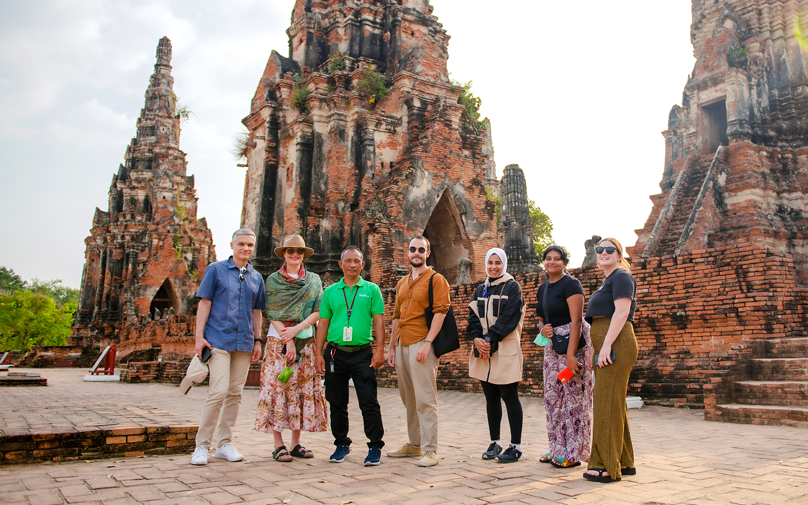 Tourists with guide at Wat Chaiwatthanaram, Ayutthaya, standing in front of ancient temple ruins.