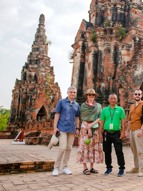 Tourists with guide at Wat Chaiwatthanaram, Ayutthaya, standing in front of ancient temple ruins.