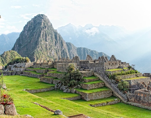 Machu Picchu ruins with mountain backdrop from lower terrace viewpoint.