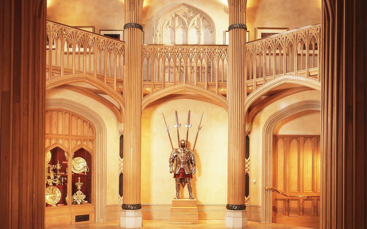 Windsor Castle interior with ornate wooden columns and a knight's armor display.