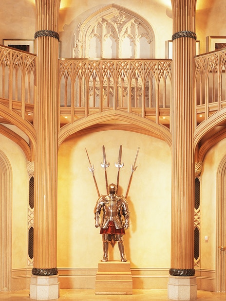 Windsor Castle interior with ornate wooden columns and a knight's armor display.