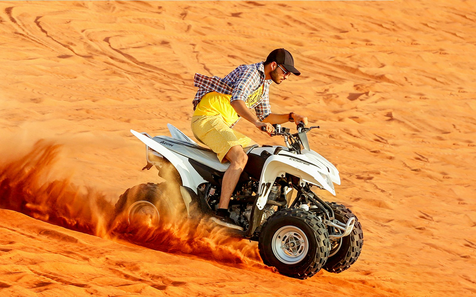 Quad biking on desert dunes during adventure tour.