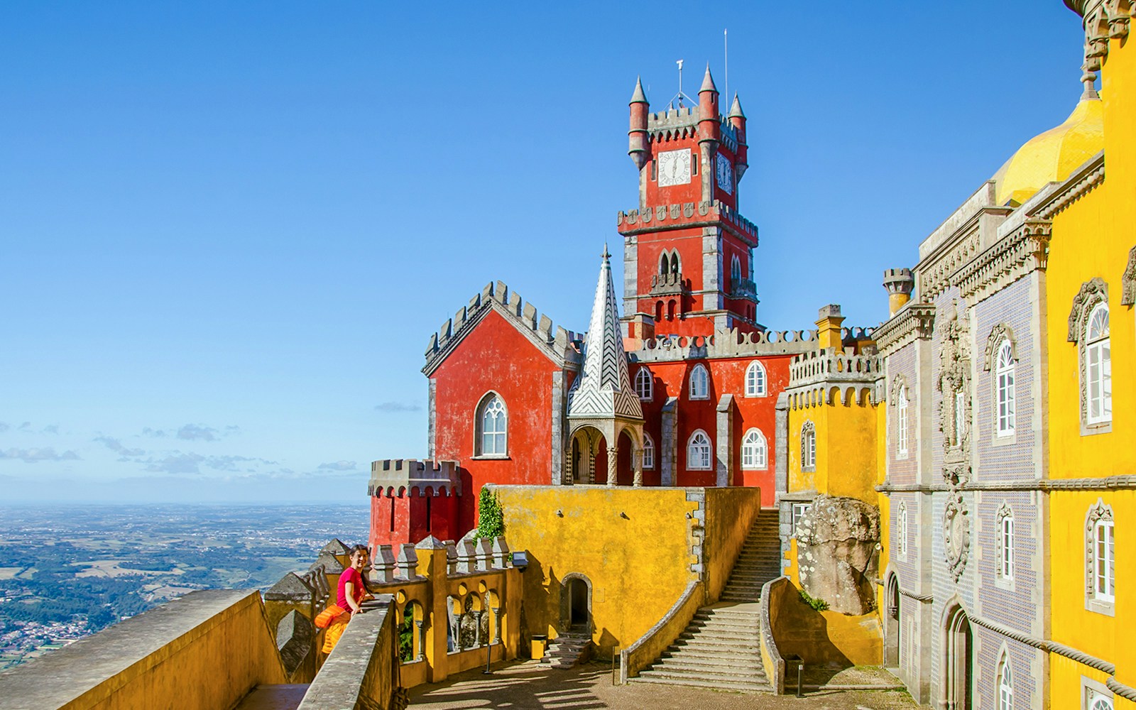 Pena Palace panoramic view in Sintra, Portugal, showcasing vibrant architecture and lush surrounding landscape.
