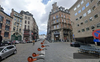 Cobbled street in Brussels with historic buildings, part of a self-guided city exploration game.