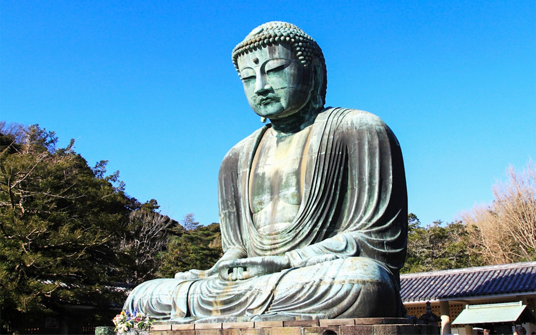 Great Buddha of Kamakura statue in Japan surrounded by trees.