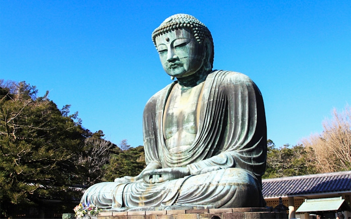 Great Buddha of Kamakura statue in Japan surrounded by trees.