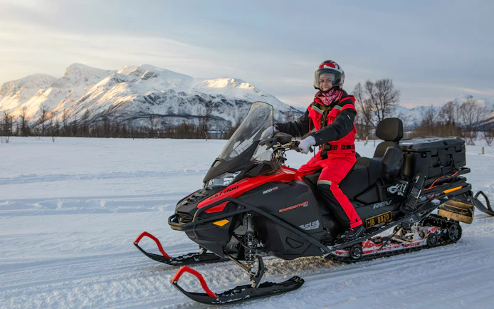 Snowmobile rider in the Lyngen Alps, Tromsø, with snowy mountains in the background.