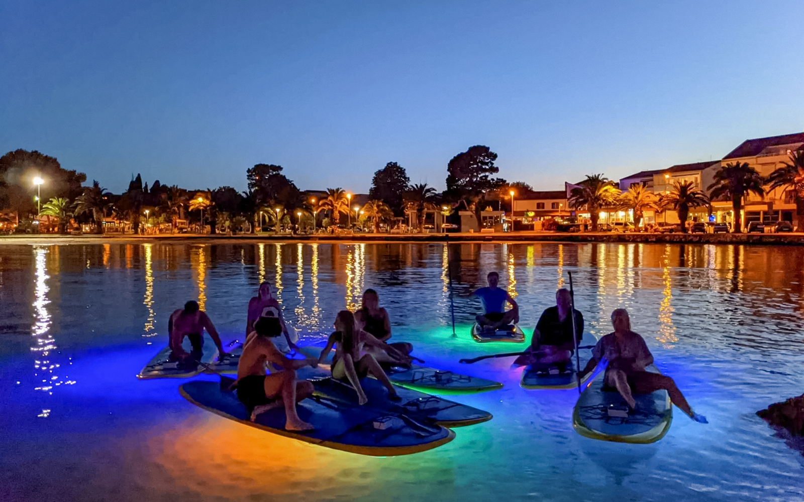 Paddleboarders on illuminated boards during SUP Glow Tour in Split at dusk.