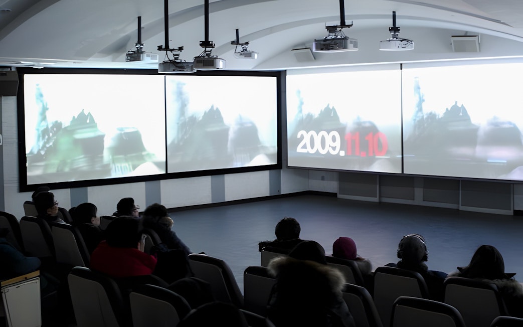 Audience watching a DMZ Tour presentation in a theater setting.