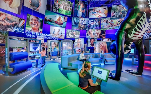 Visitors engaging with interactive human biology exhibit, using digital screens and models.