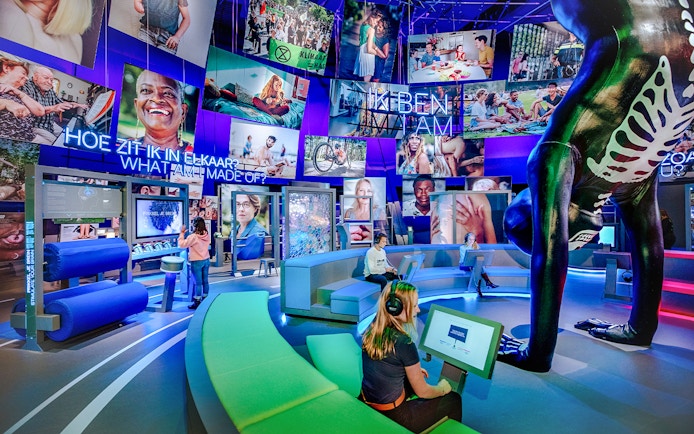 Visitors engaging with interactive human biology exhibit, using digital screens and models.