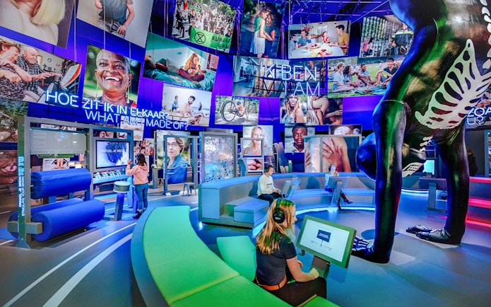 Visitors engaging with interactive human biology exhibit, using digital screens and models.