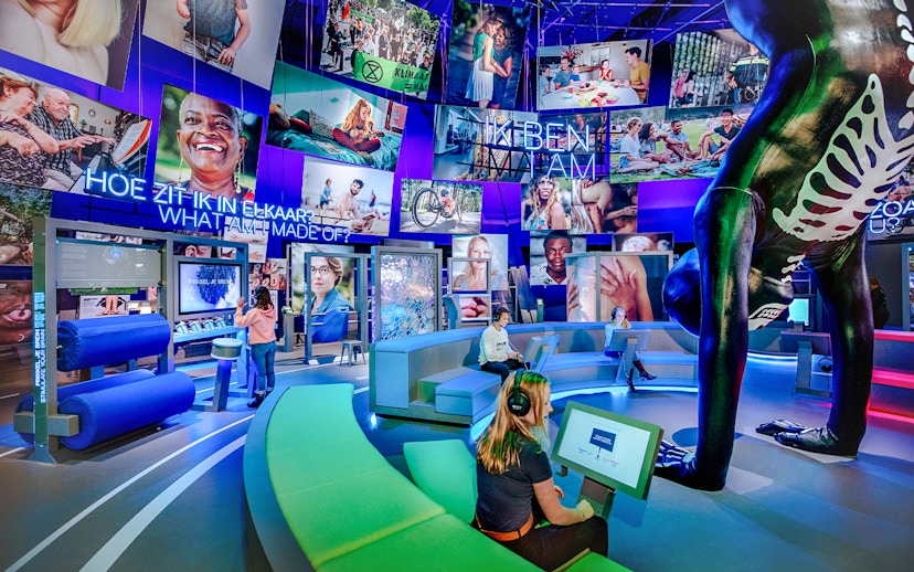 Visitors engaging with interactive human biology exhibit, using digital screens and models.