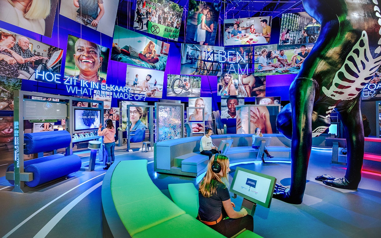 Visitors engaging with interactive human biology exhibit, using digital screens and models.