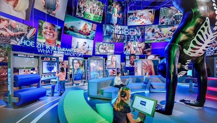 Visitors engaging with interactive human biology exhibit, using digital screens and models.