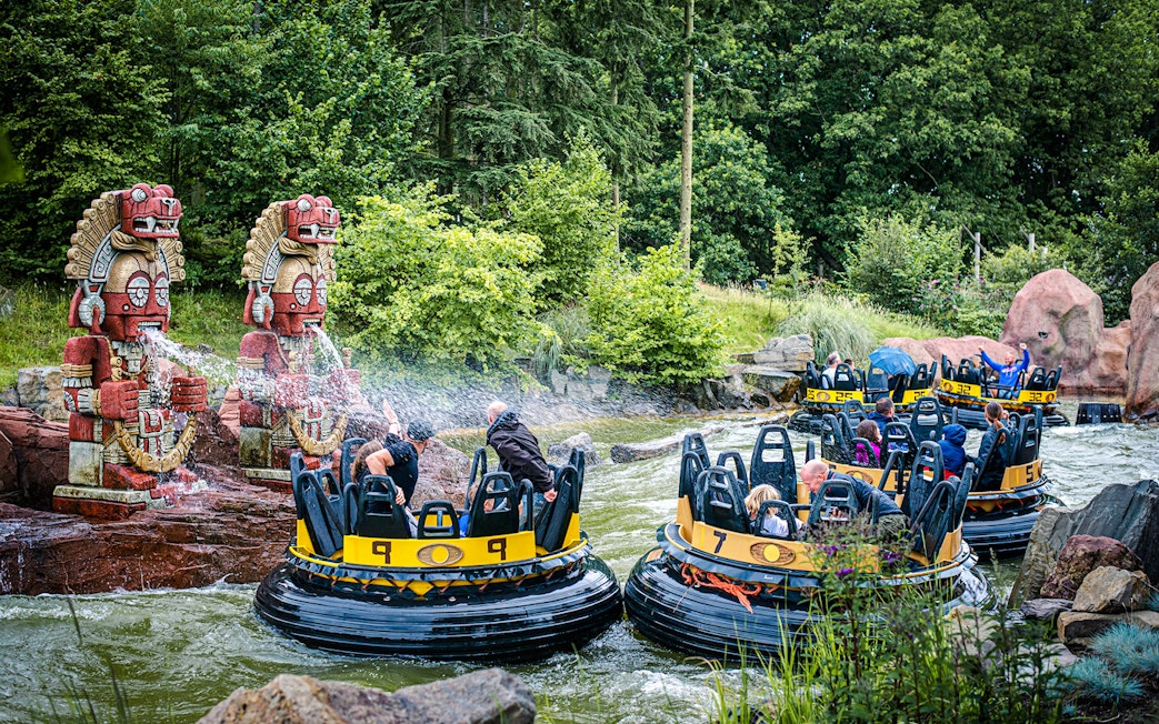 Guests on a water ride at Efteling in Amsterdam with decorative statues spraying water.