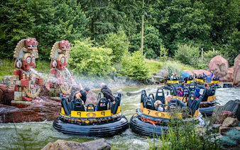 Guests on a water ride at Efteling in Amsterdam with decorative statues spraying water.