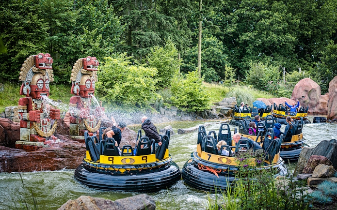 Guests on a water ride at Efteling in Amsterdam with decorative statues spraying water.