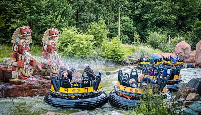 Guests on a water ride at Efteling in Amsterdam with decorative statues spraying water.