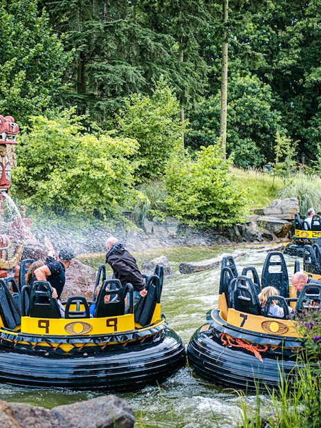 Guests on a water ride at Efteling in Amsterdam with decorative statues spraying water.