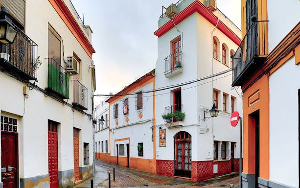 Narrow street in the Jewish Quarter of Córdoba with traditional white and orange buildings.
