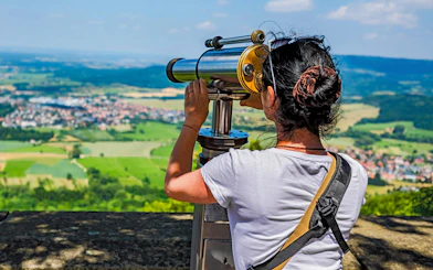 Woman using telescope on Hohenzollern Castle observation deck, Germany.