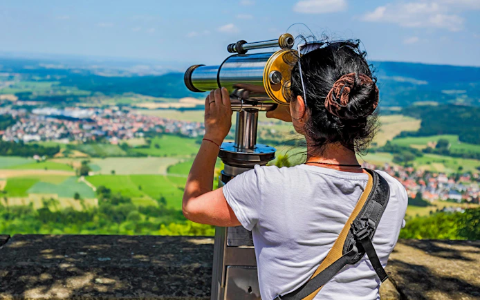 Woman using telescope on Hohenzollern Castle observation deck, Germany.