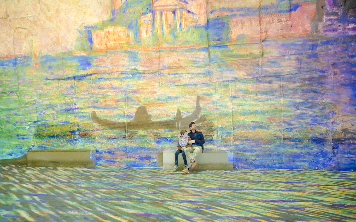 Visitors enjoying Monet projections at Carrières des Lumières, France.