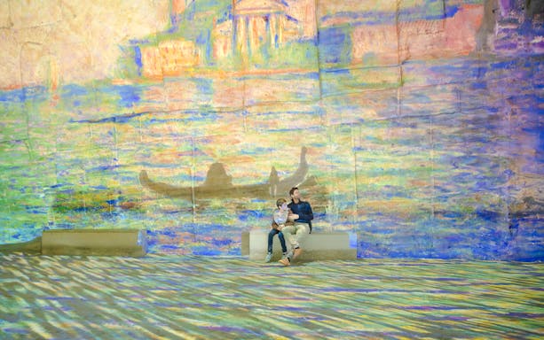 Visitors enjoying Monet projections at Carrières des Lumières, France.