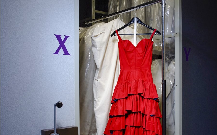 Red dress on display at Palais Galliera, Paris fashion museum exhibit.