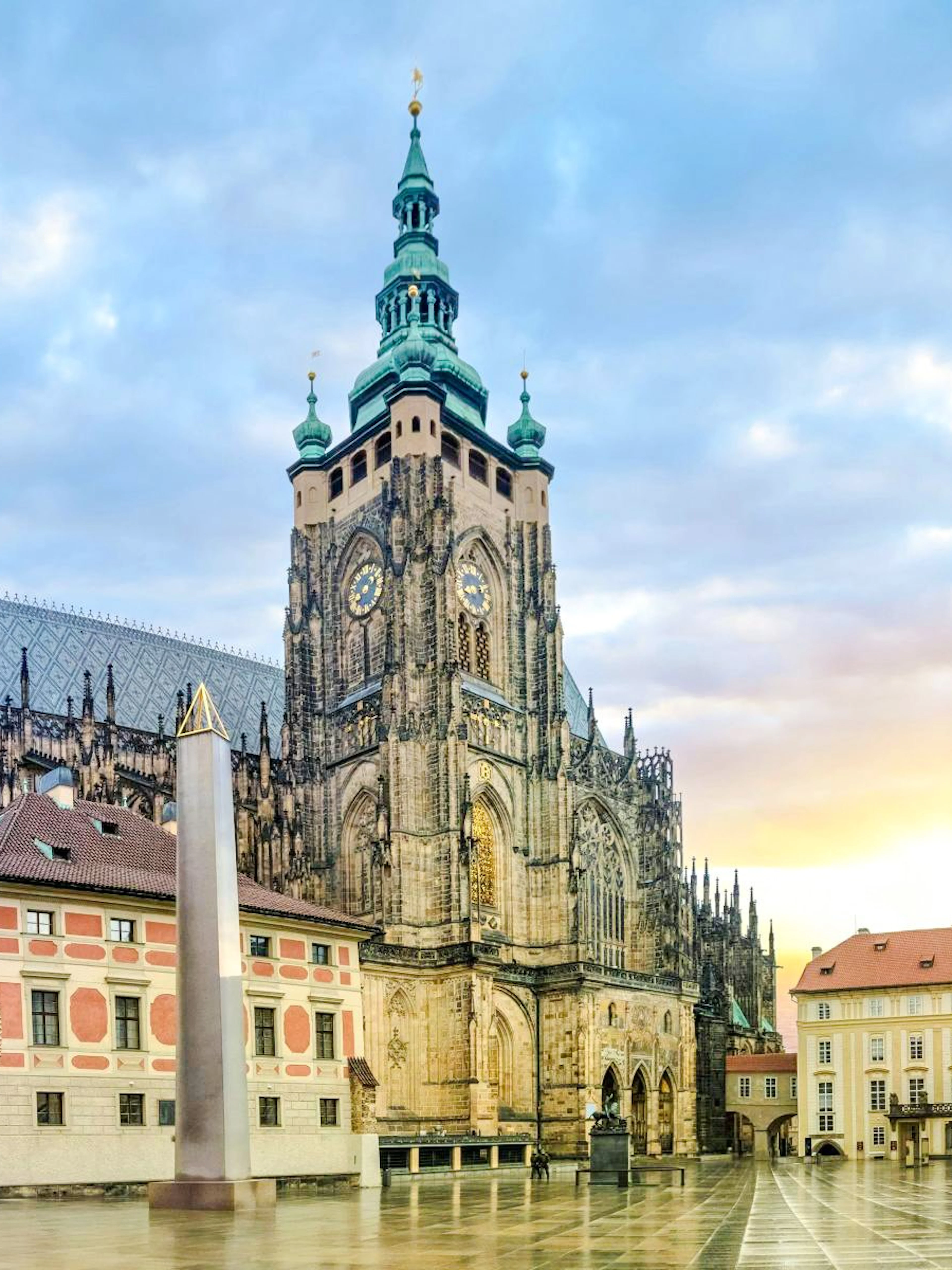 Prague Castle exterior with St. Vitus Cathedral spires at sunrise.
