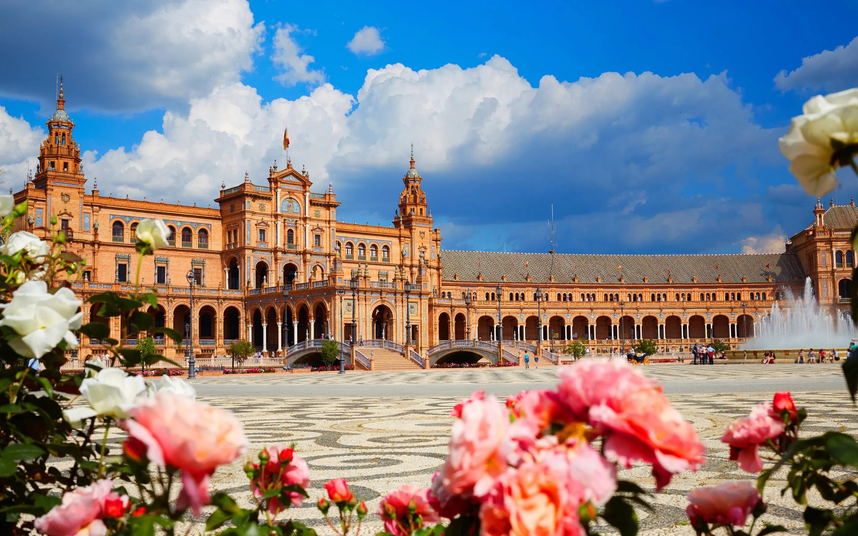Plaza de España in Seville, Spain with vibrant flowers and fountain in foreground.