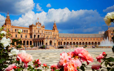Plaza de España in Seville, Spain with vibrant flowers and fountain in foreground.