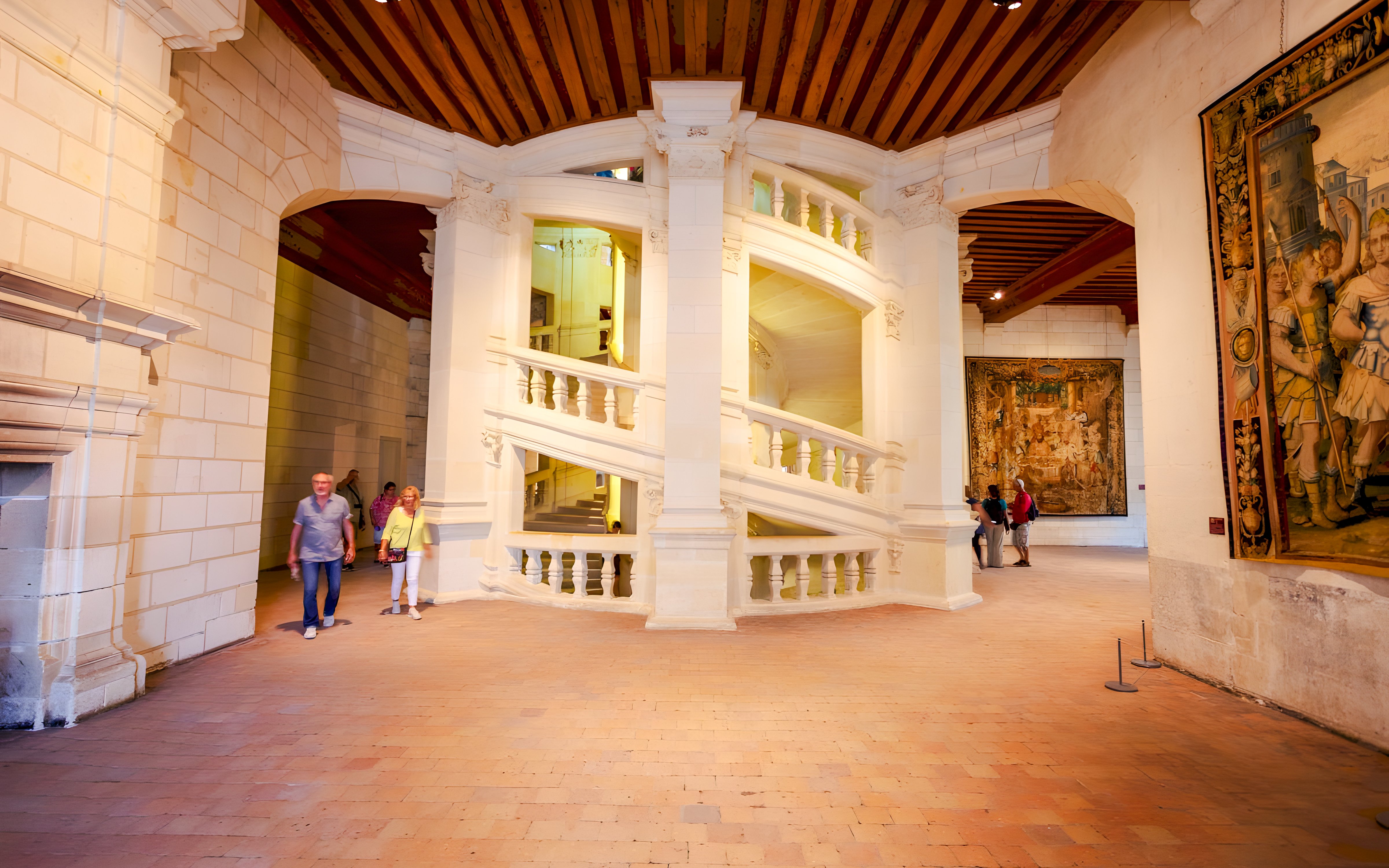 Chambord Castle interior with double helix staircase and visitors exploring.