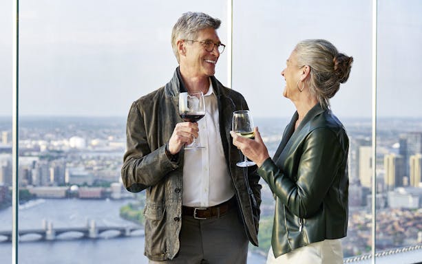 Couple enjoying drinks with a view of Boston skyline and Charles River.