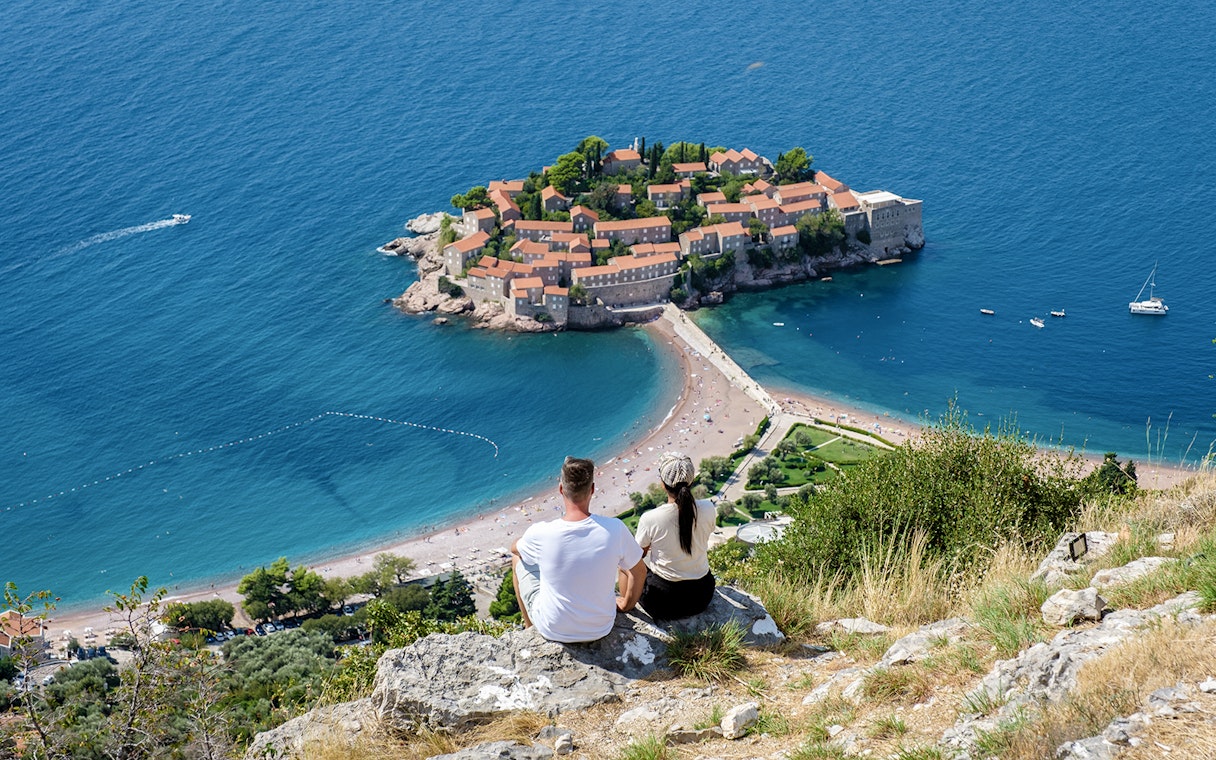 Couple overlooking Sveti Stefan island and beach in Montenegro.