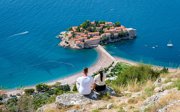 Couple overlooking Sveti Stefan island and beach in Montenegro.