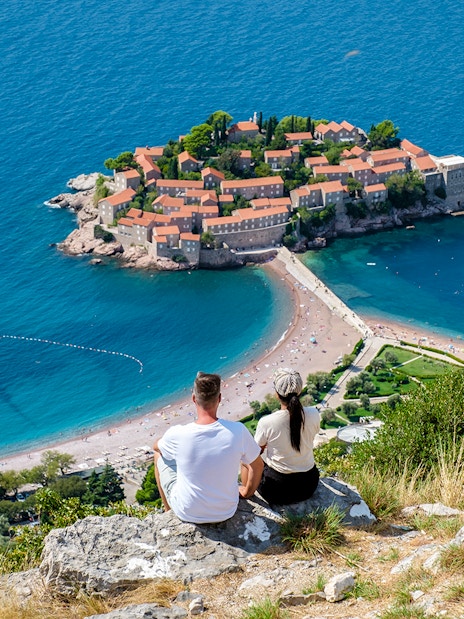 Couple overlooking Sveti Stefan island and beach in Montenegro.